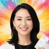 推し活を楽しみ、自信に満ちた笑顔でこちらを見つめる独身女性。背景の輝く色は、彼女の充実した人生を象徴しており、「推し活して何が悪い？」という記事のテーマを表すアイキャッチ画像。